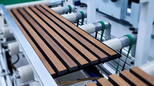 PUR gluing line — wooden slats glued to a felt backing and pressed into a finished wall panel.